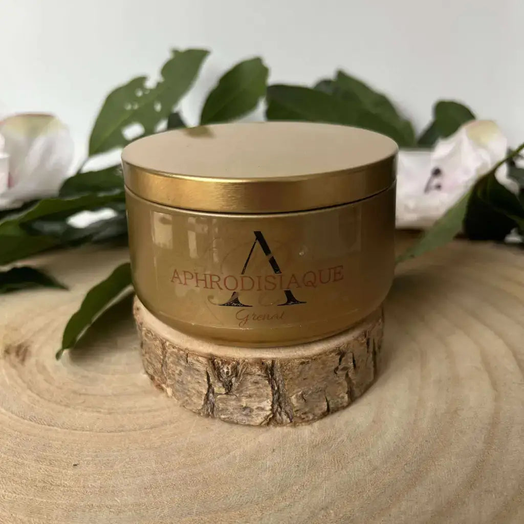 Bougie Aphrodisiaque en Grenat dans un contenant doré sur un support en bois avec des feuilles décoratives