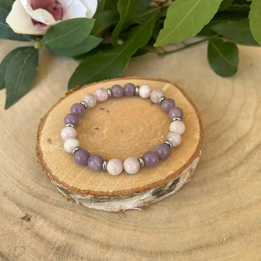Bracelet kunzite lépidolite d'Aura de Roche avec perles mauves et roses sur un support en bois