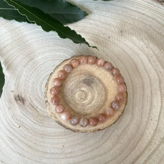 Bracelet Pierre de Soleil en perles polies sur un support en bois naturel