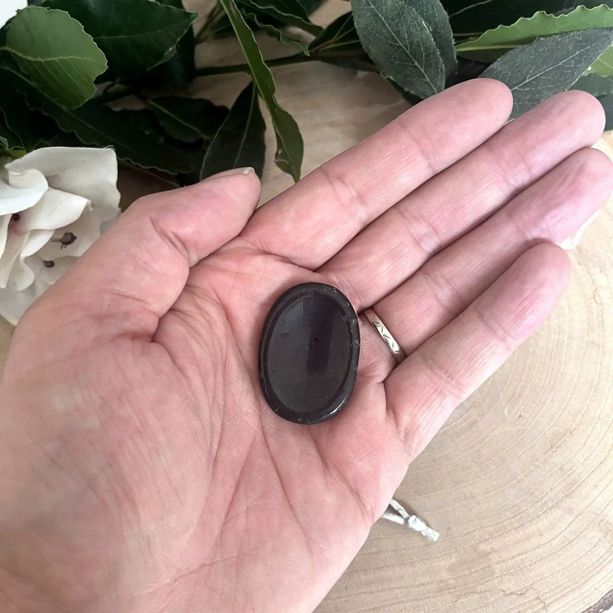 Galet anti-stress en tourmaline noire tenu dans la main