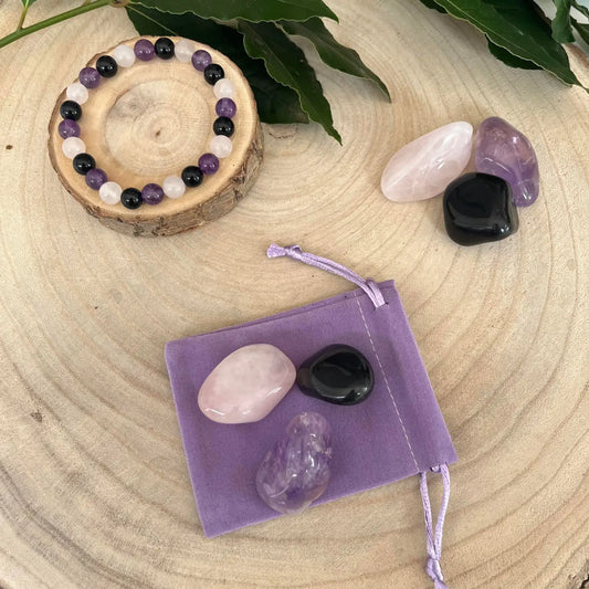 Bracelet en pierres naturelles pour deuil avec améthyste, onyx noir, et quartz rose sur un fond en bois