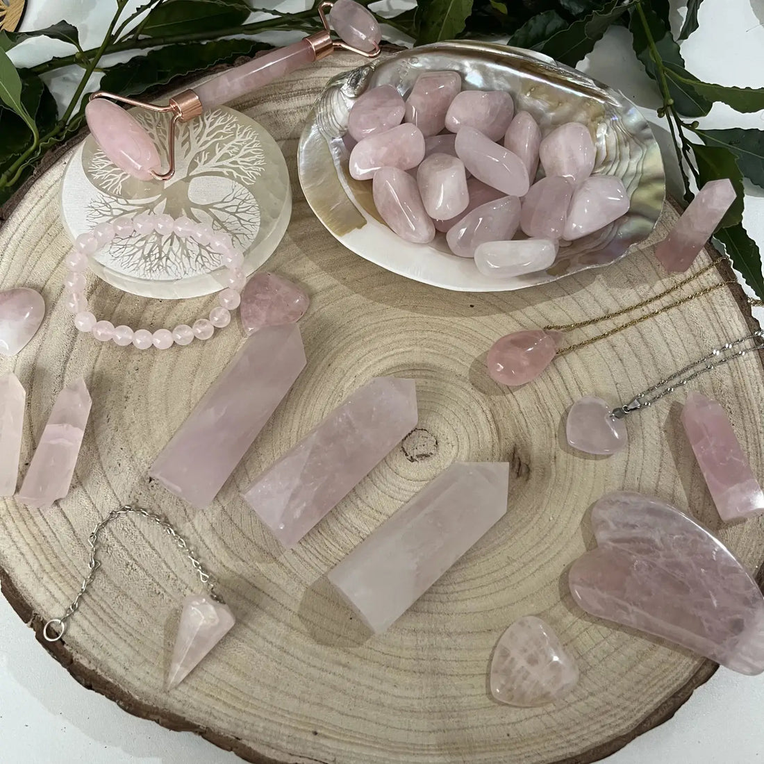 Collection de Quartz Rose Pierre Naturelle incluant pendentifs, bracelets et galets sur une surface en bois