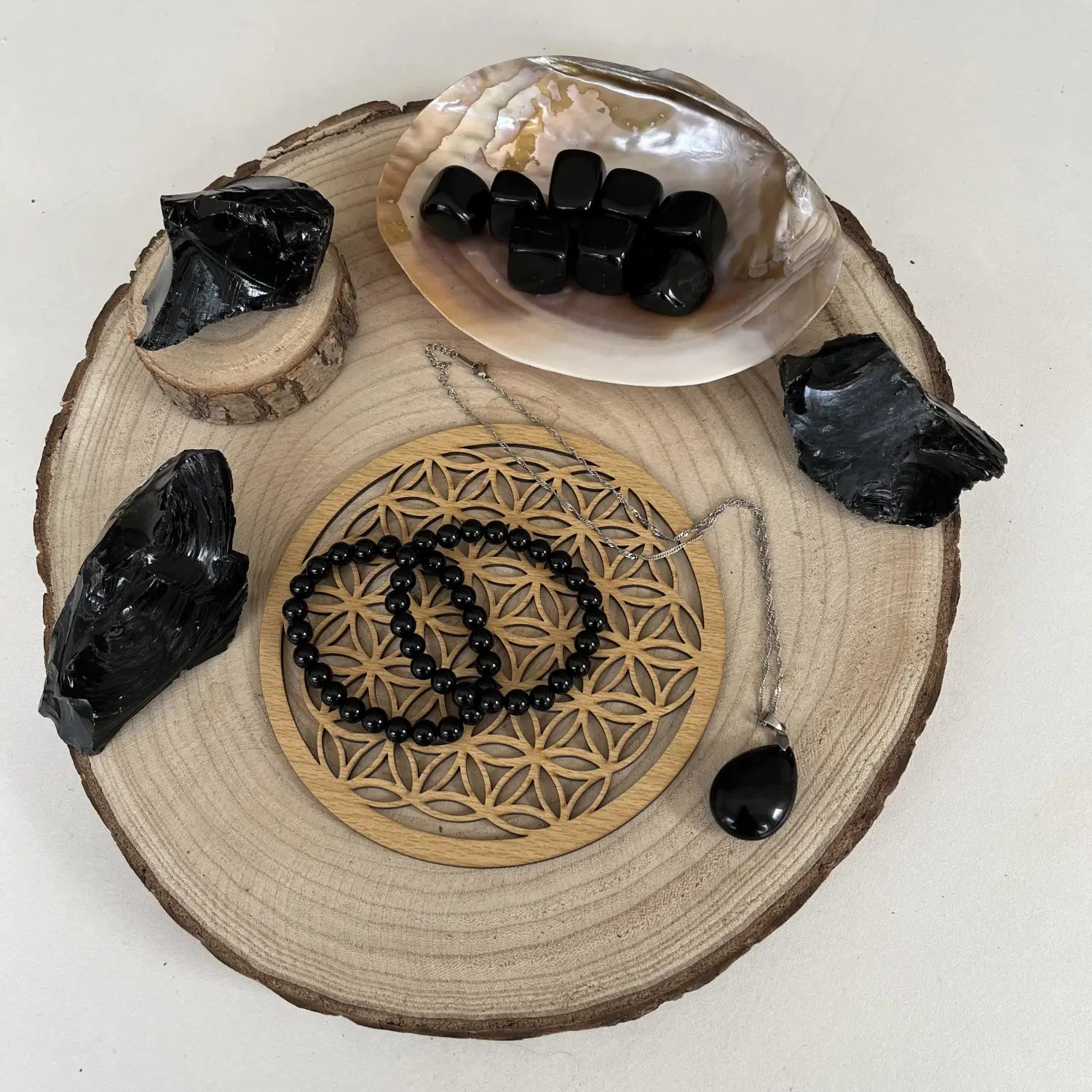 Collection d'objets en obsidienne noire comprenant pendentifs, bracelets et pierres sous forme brute et roulée