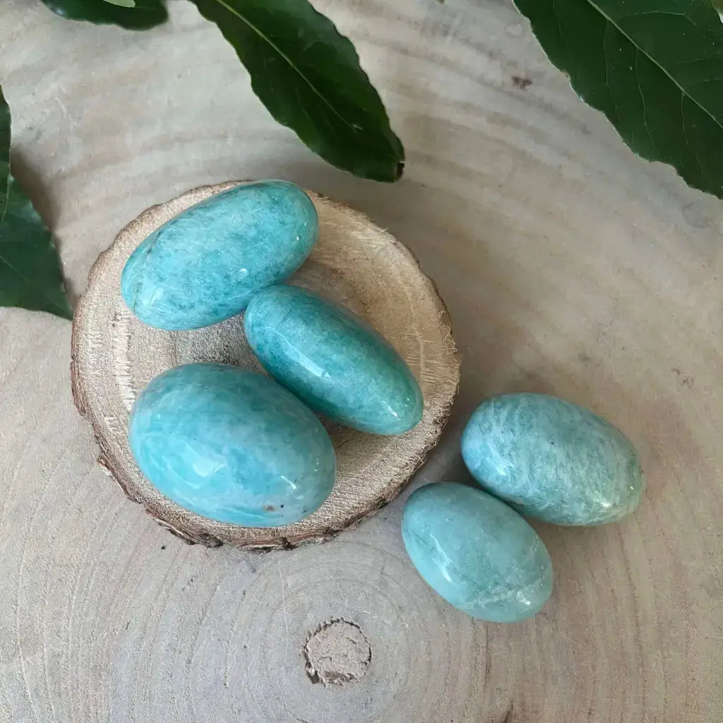 Cinq pierres roulées en amazonite d'Aura de Roche sur une tranche de bois