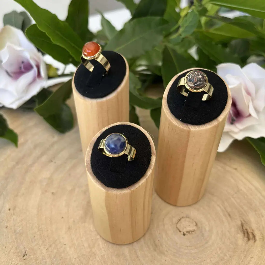Bague ajustable ronde Dorée Aura de Roche avec pierre colorée présentée sur socle en bois