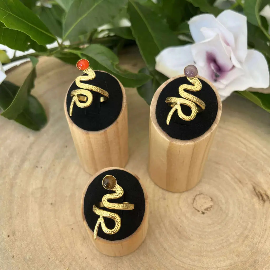 Bague ajustable Serpent en métal doré avec pierre colorée sur présentoir en bois Aura de Roche