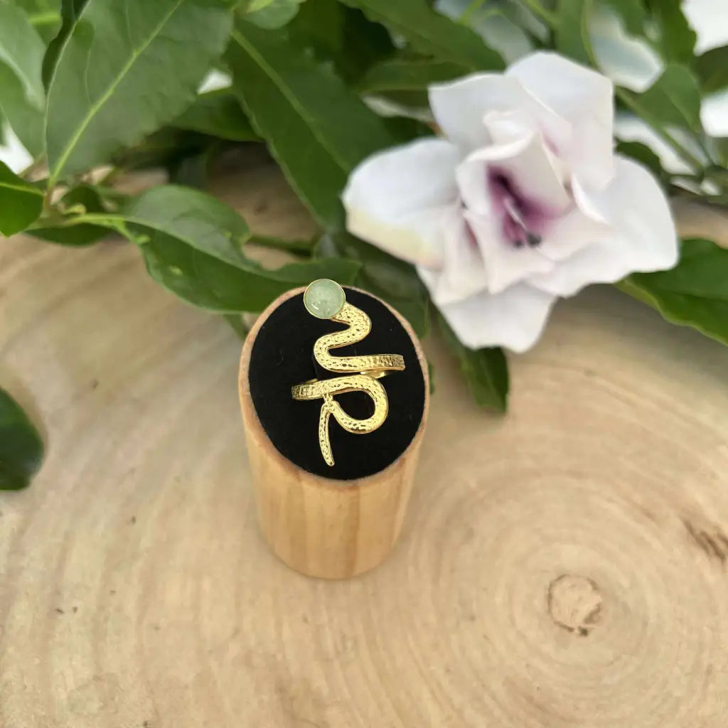 Bague ajustable Serpent dorée avec pierre verte présentée sur support en bois Aura de Roche