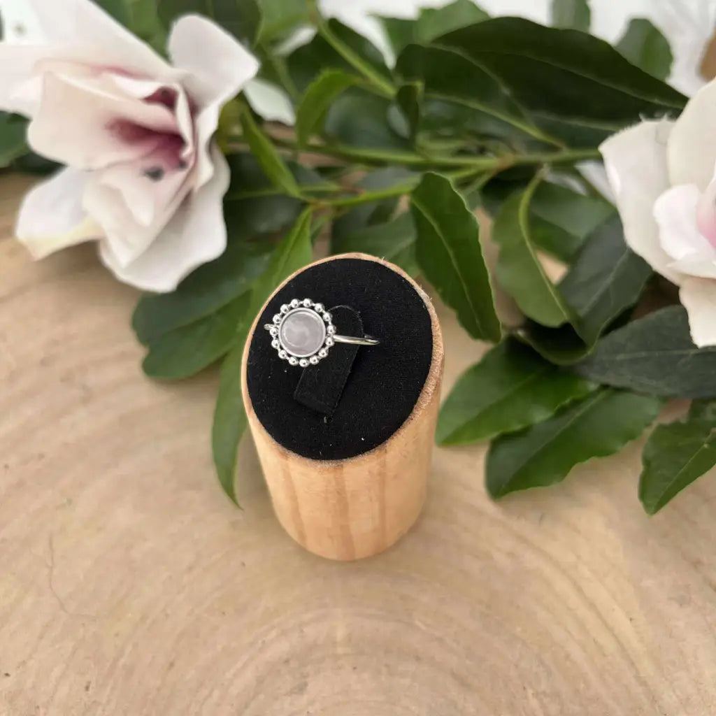 Bague ajustable Solara en argent avec pierre ronde délicate présentée sur support en bois