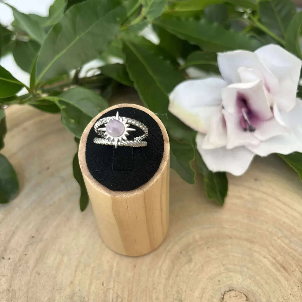 Bague ajustable Soleil en argent avec pierre violette posée sur support en bois naturel