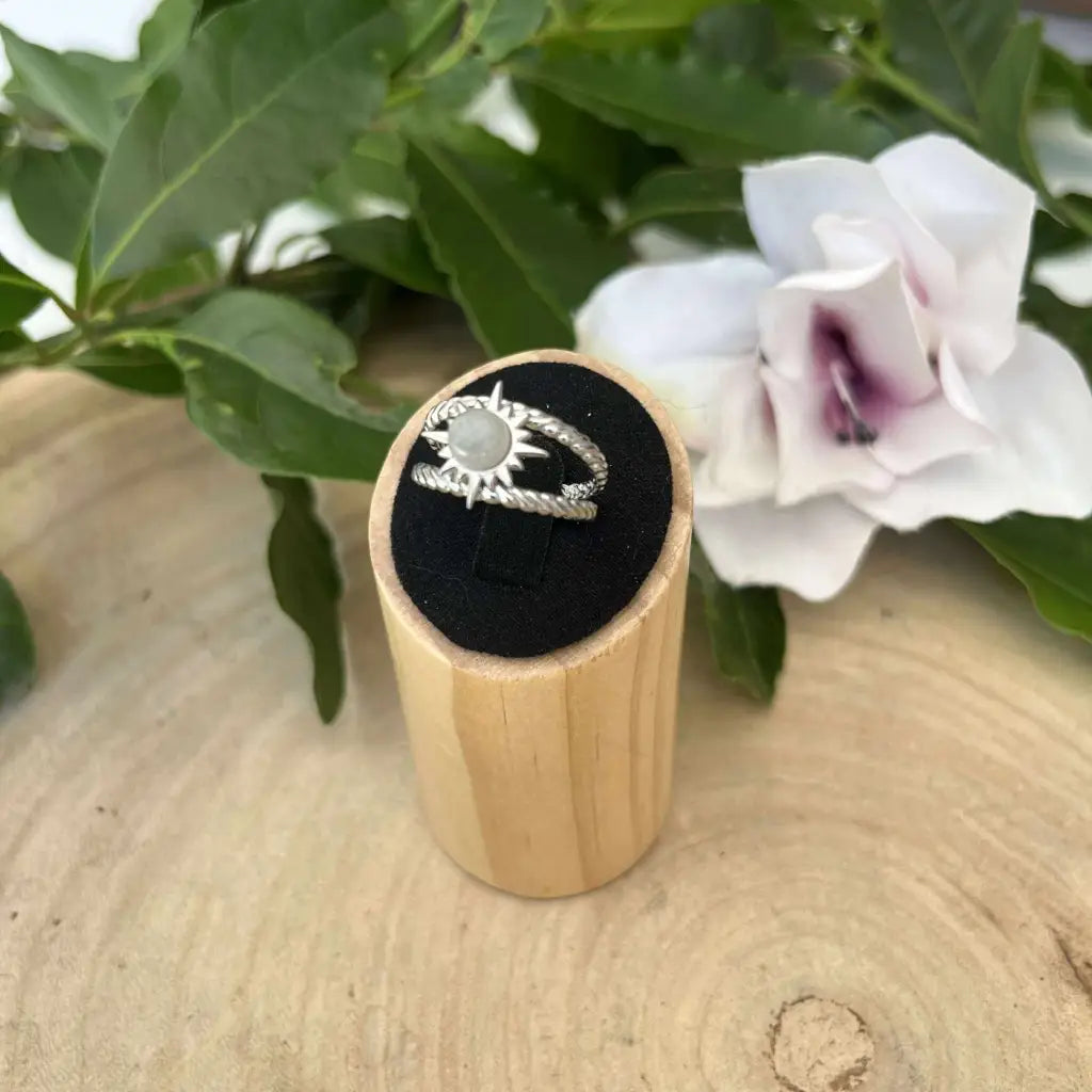 Bague ajustable Soleil en argent avec pierre centrale présentée sur support en bois naturel