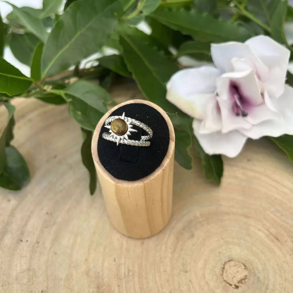 Bague ajustable Soleil en argent avec pierre jaune sur support en bois avec fleurs blanches