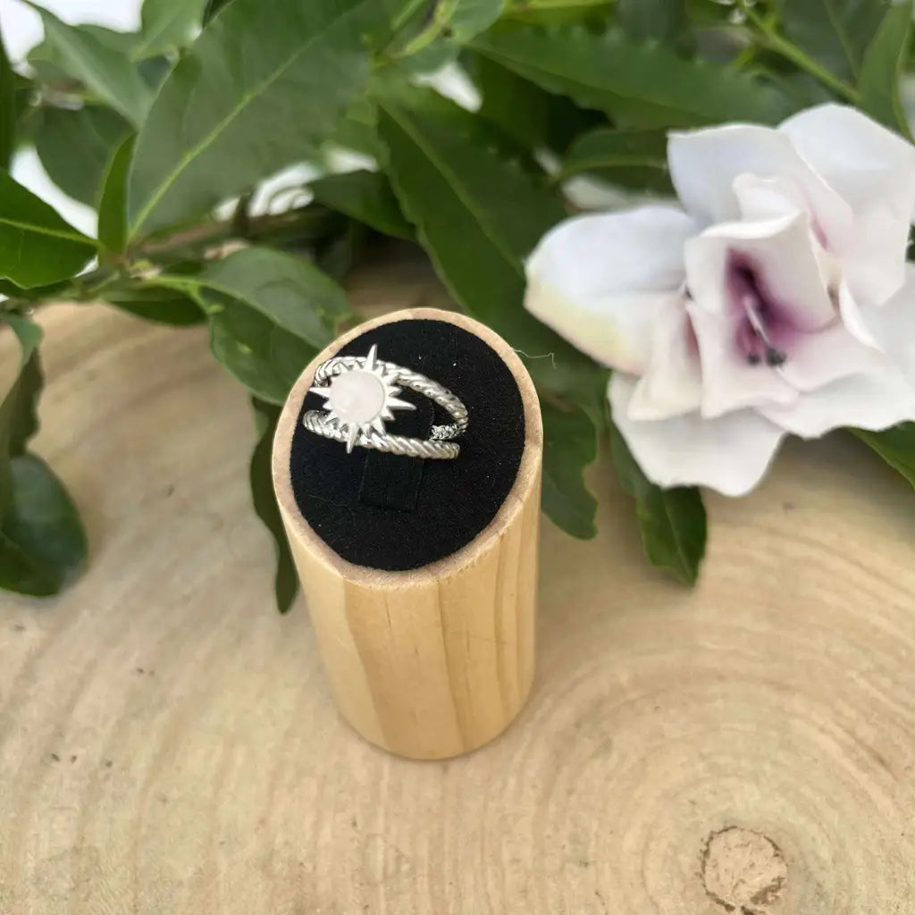 Bague ajustable Soleil en argent avec design rayons de soleil présentée sur support en bois naturel