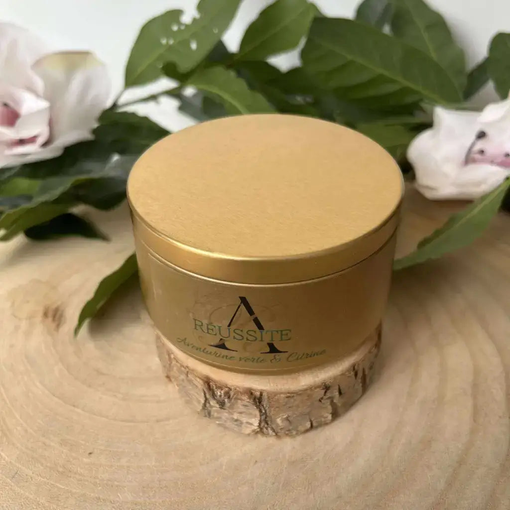 Bougie Réussite d'Aura de Roche avec couvercle doré, entourée de feuillage naturel