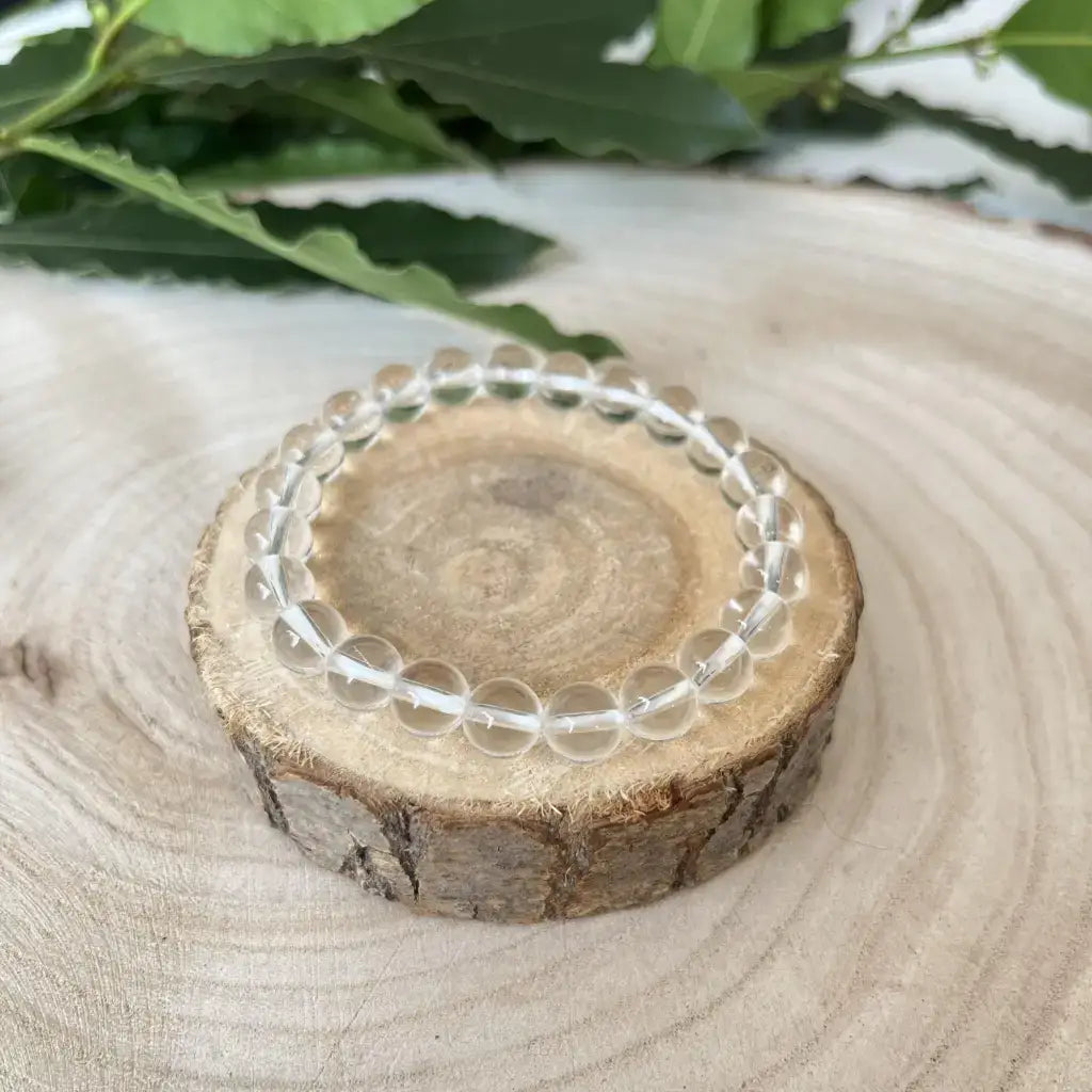 Bracelet Cristal de Roche en perles transparentes sur un support en bois naturel