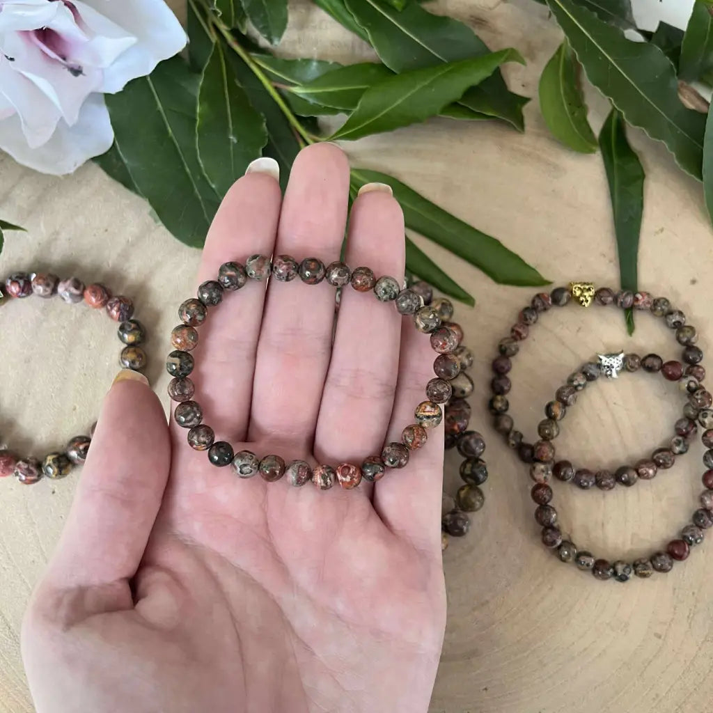 Bracelet en Jaspe Léopard avec perles naturelles, présenté dans une main, entouré d'autres bracelets.