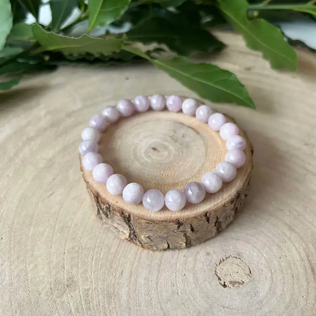 Bracelet en Kunzite avec perles roses douces sur un support en bois naturel