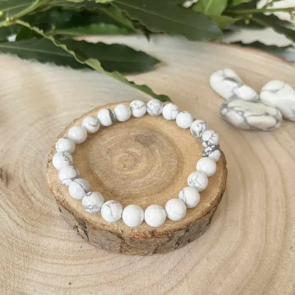 Bracelet Howlite Blanche en perles blanches avec motifs gris sur un support en bois