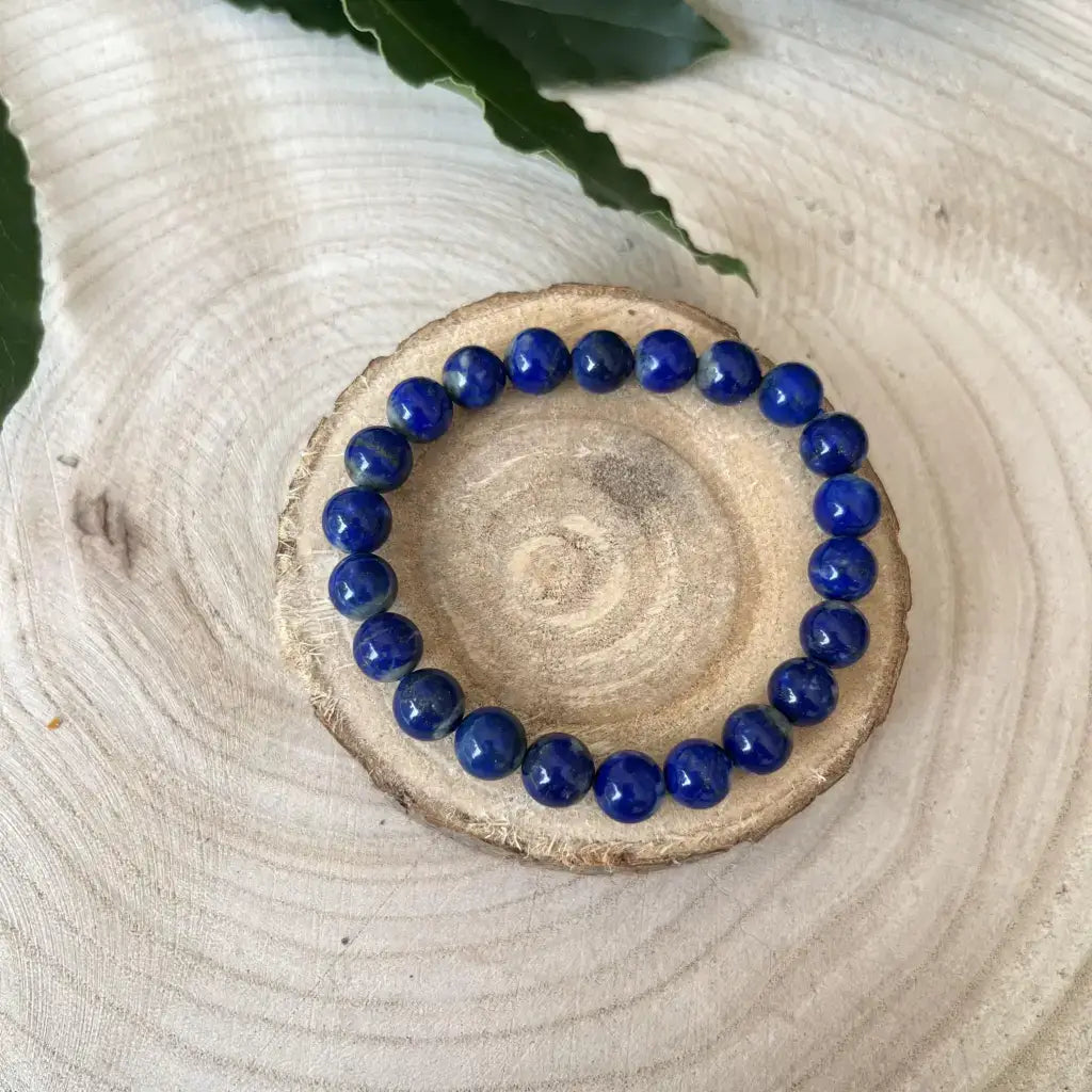 Bracelet Lapis Lazuli en perles bleues profondes sur un support en bois naturel