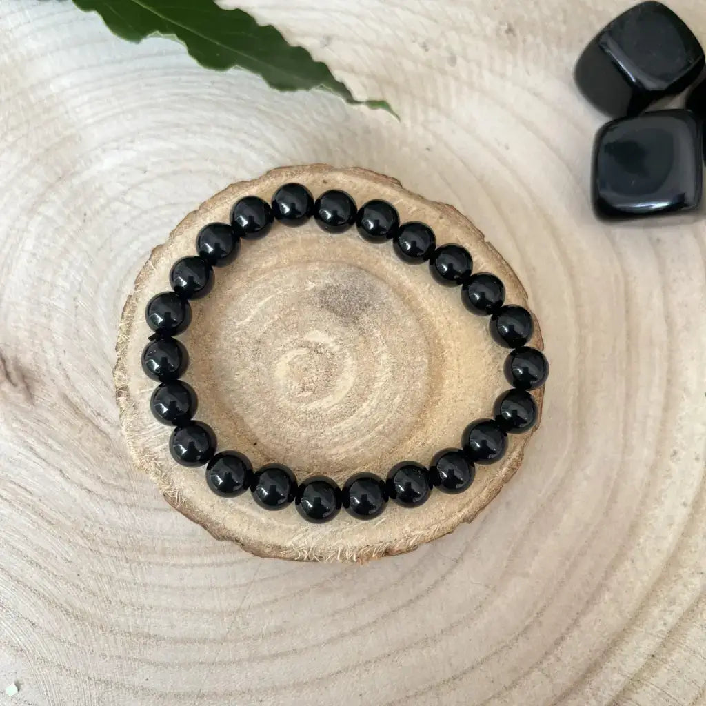 Bracelet Obsidienne Noire élégant sur un support en bois, avec perles brillantes et design simple