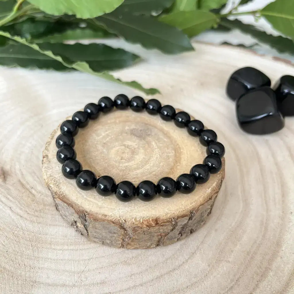Bracelet Obsidienne Noire en perles brillantes sur un support en bois naturel