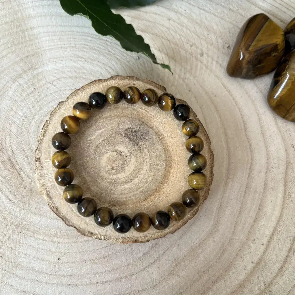 Bracelet Œil de Tigre : Force et Protection sur un support en bois naturel, mettant en valeur ses pierres brillantes.