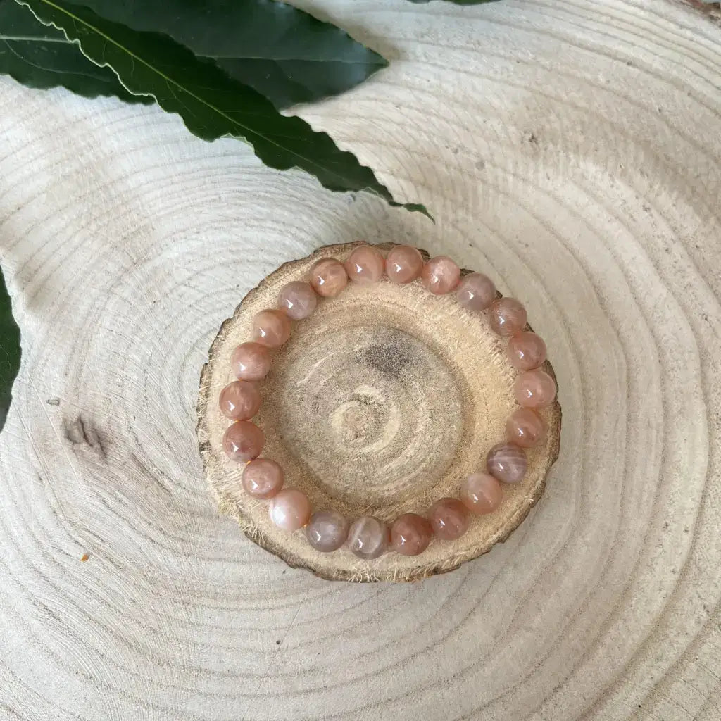 Bracelet Pierre de Soleil en perles polies sur un support en bois naturel