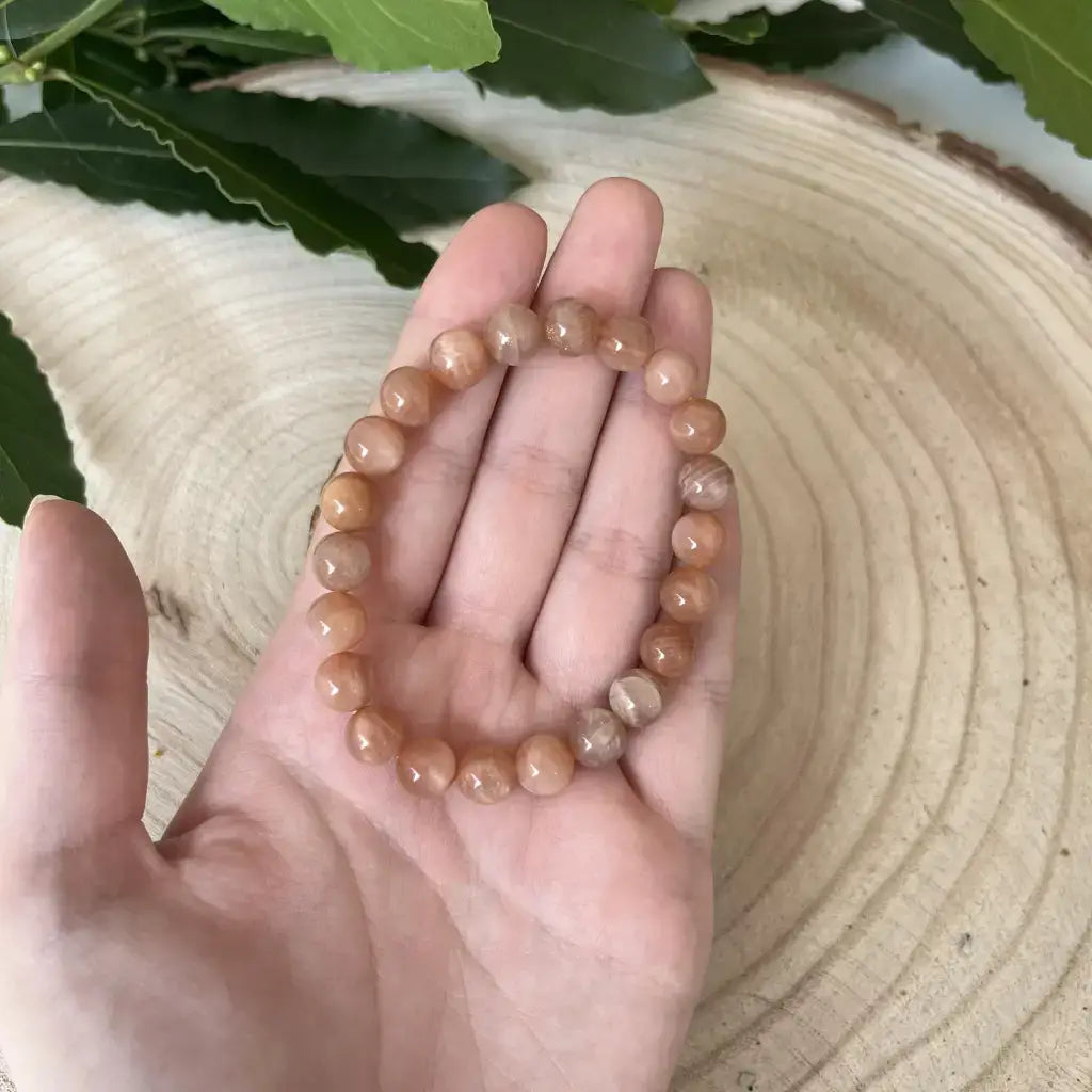 Bracelet Pierre de Soleil en perles naturelles porté à la main sur une table en bois