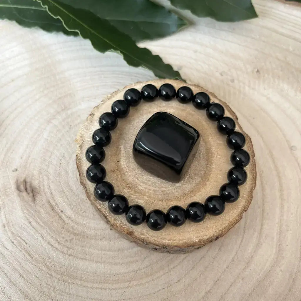 Bracelet & Pierre Obsidienne, bracelet en perles noires brillantes sur un support en bois naturel