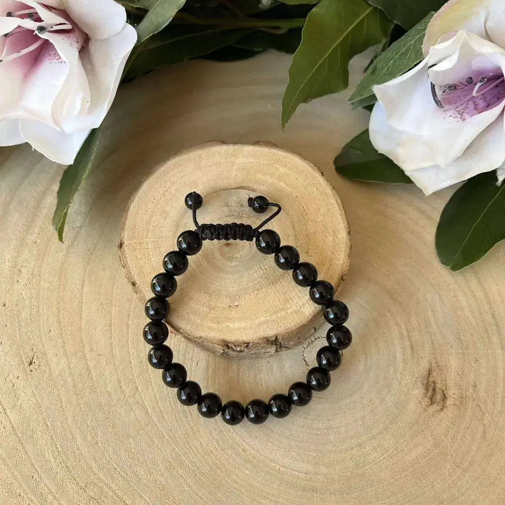 Bracelet Shambala Obsidienne Noire en pierres naturelles sur un support en bois décoratif