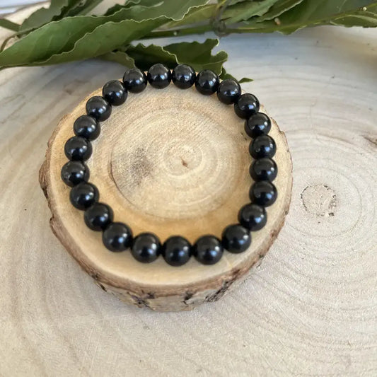 Bracelet Bouclier Shungite en perles noires naturelles sur un support en bois