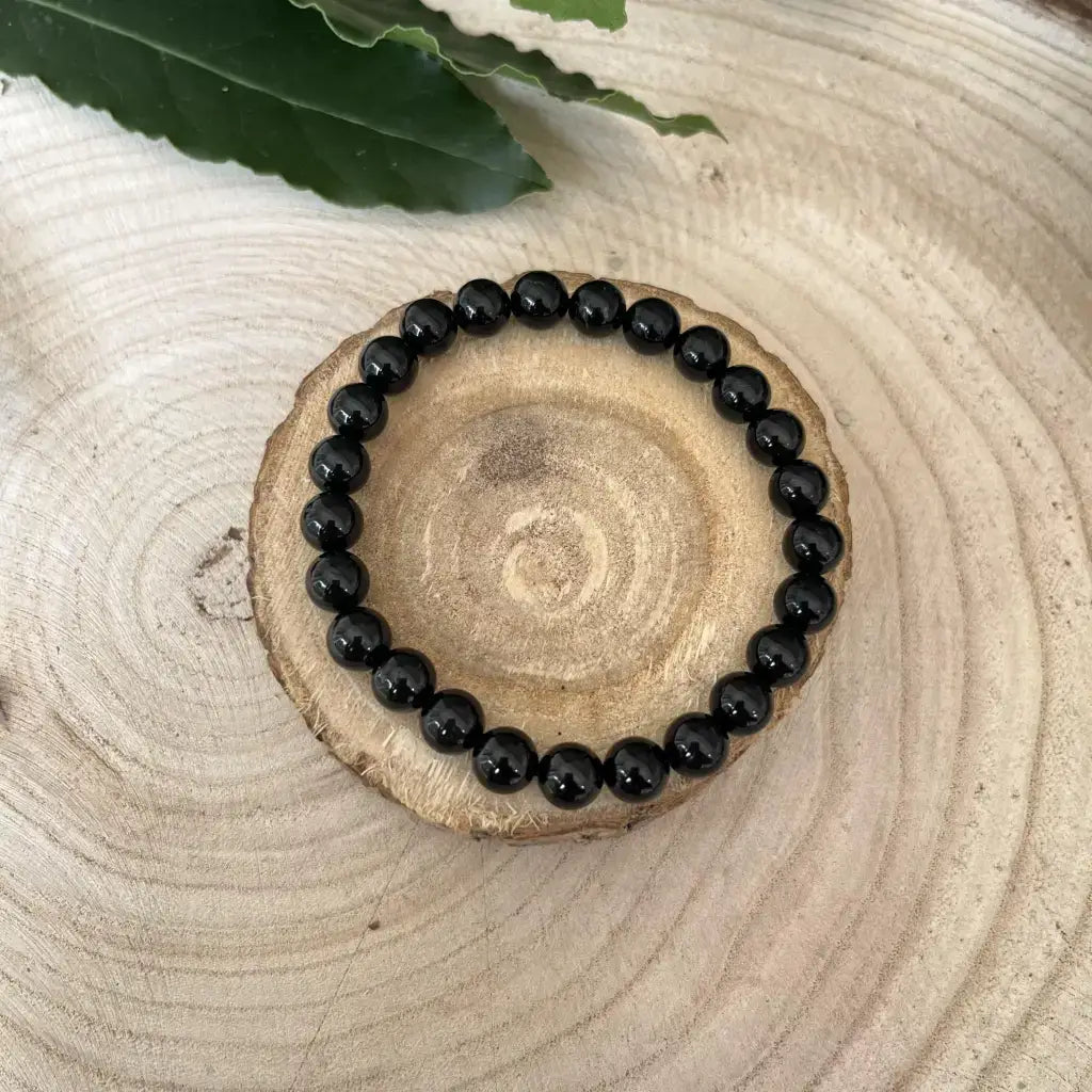 Bracelet Tourmaline Noire en perles brillantes sur un support en bois naturel