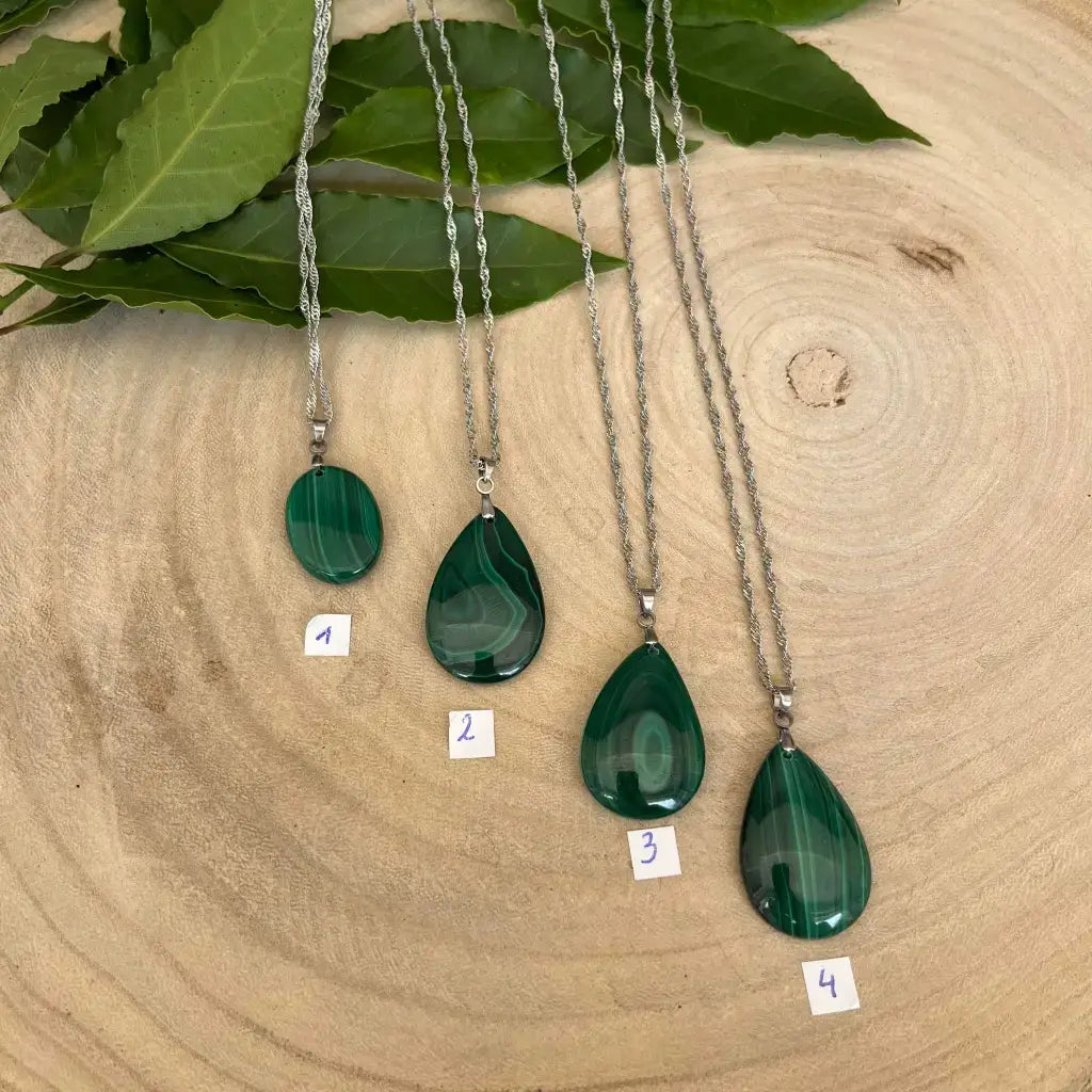 Quatre colliers en Malachite avec pendentifs en forme de goutte sur un fond en bois