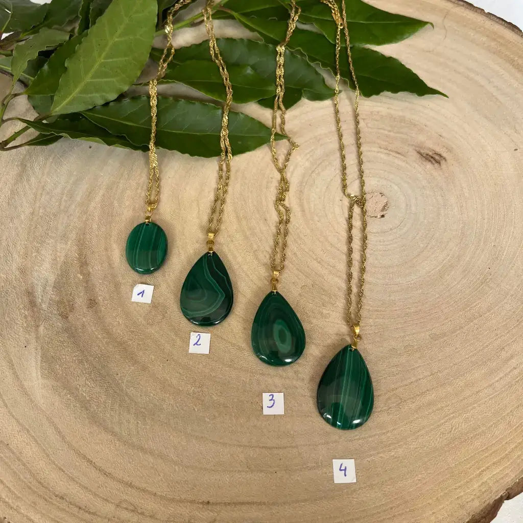 Quatre colliers en Malachite avec pendentifs en forme de goutte sur un support en bois