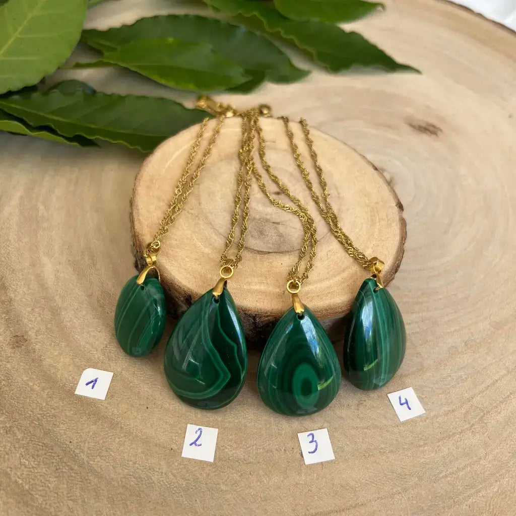 Quatre colliers en Malachite avec pendentifs en forme de goutte sur support en bois