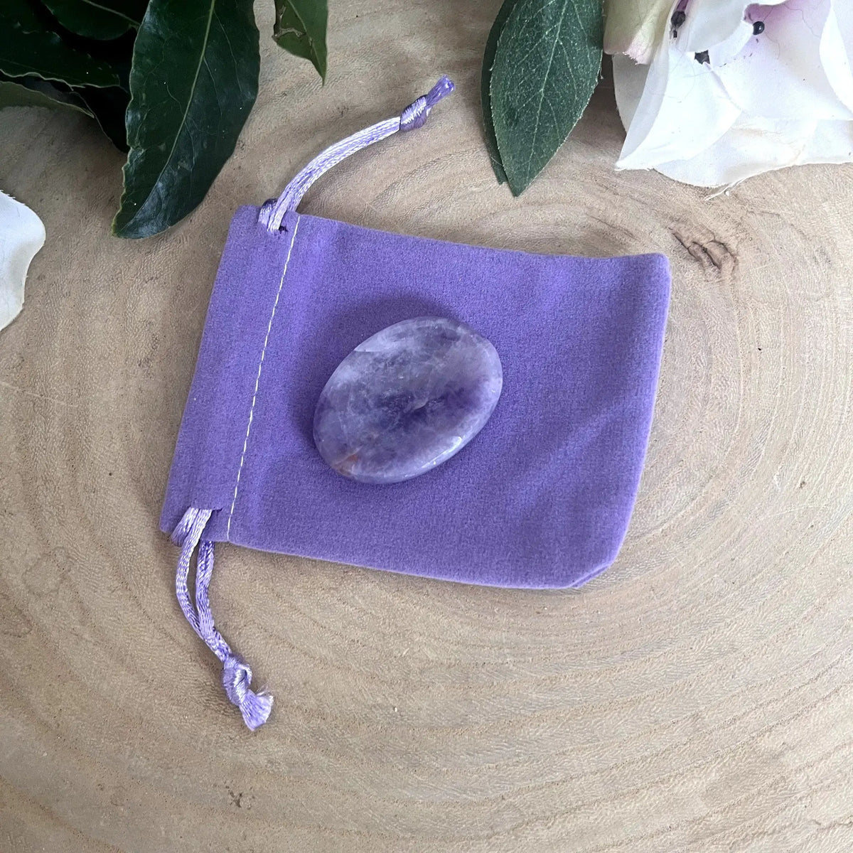 Galet anti-stress en améthyste posé sur son pochon violet