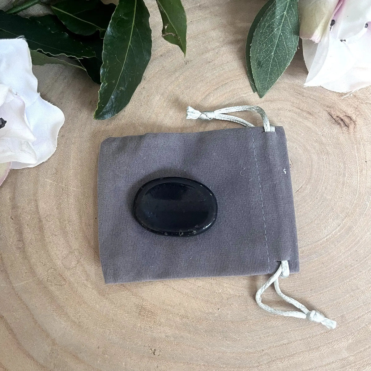 Galet anti-stress en tourmaline noire posé sur son pochon gris