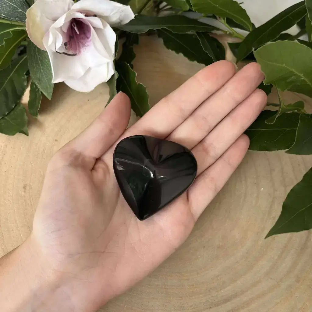 Galet en forme de cœur – Obsidienne Œil Céleste. Galet poli Aura de Roche, noir brillant posé dans une main