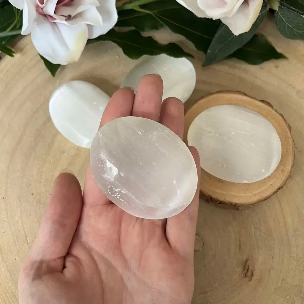 Galet en Sélénite naturel dans une main, mettant en avant sa texture et sa luminosité