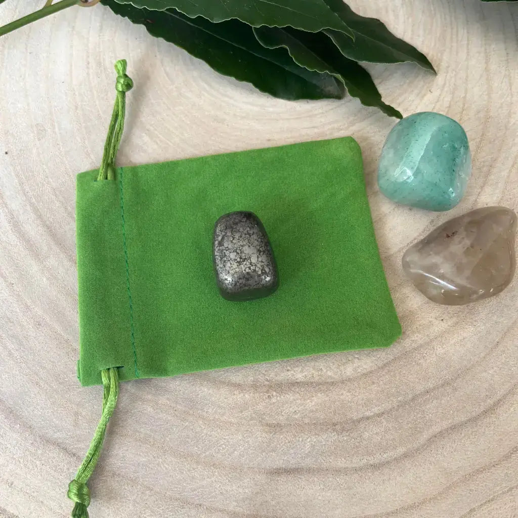 Kit de Réussite avec Pierres Naturelles comprenant une pierre sombre et deux pierres claires dans un sac vert.