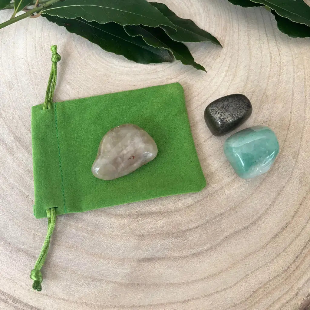 Kit de Réussite avec Pierres Naturelles comprenant trois pierres dans un sac vert sur une surface en bois