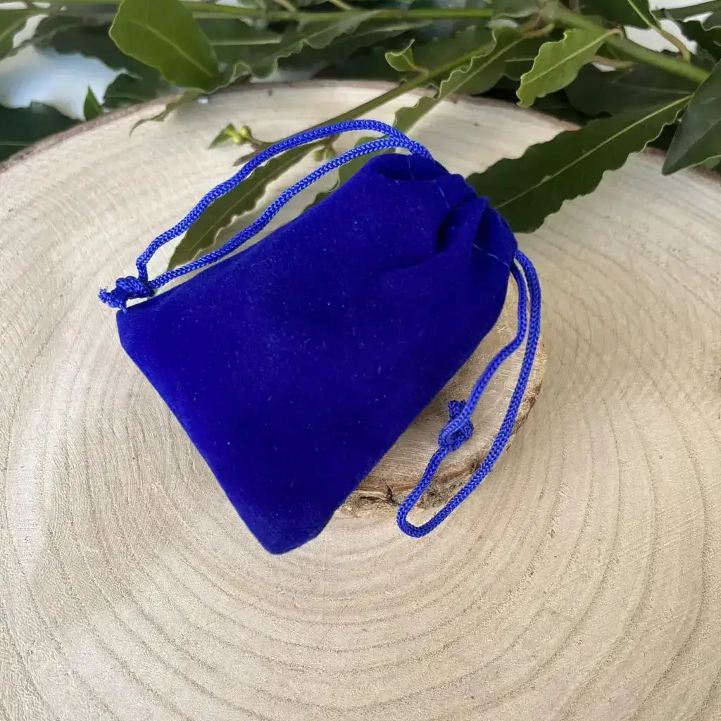 Kit Pierre Naturelle Sommeil dans une pochette bleue en velours sur un support en bois naturel