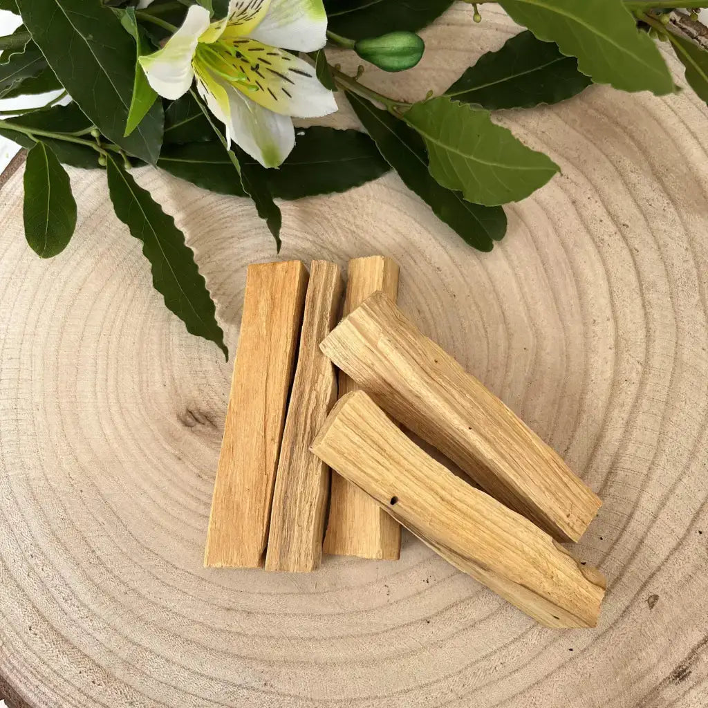 Palo Santo Bois Sacrée en morceaux sur une planche en bois avec des feuilles vertes en arrière-plan