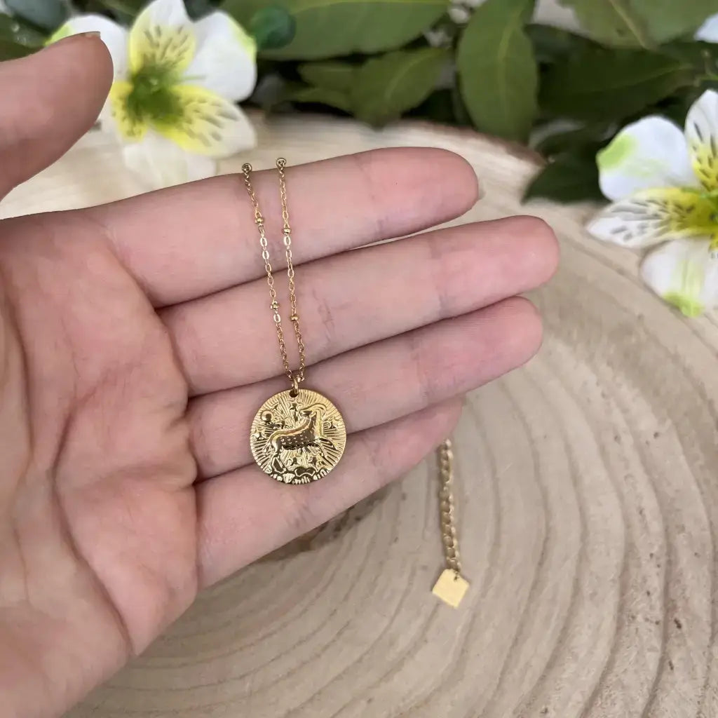 Pendentif Bélier avec Pierre de Pouvoir suspendu sur une chaîne en or, déposé sur une surface en bois