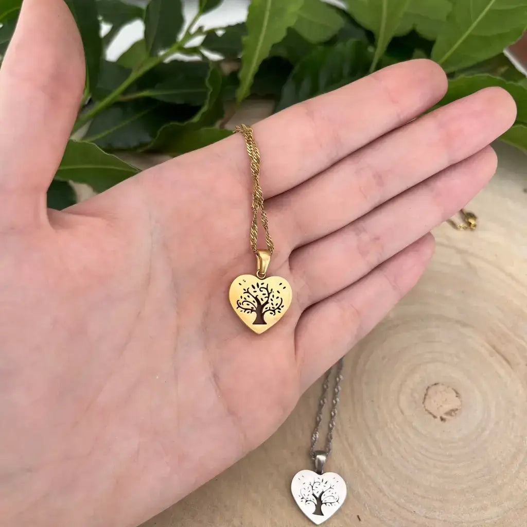 Pendentif Cœur avec Arbre de Vie en métal doré tenu dans la paume, chaîne torsadée, autre pendentif argenté en arrière