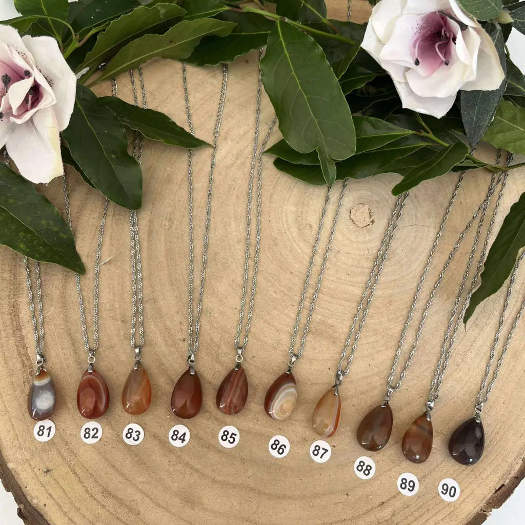 Collection de colliers pendentif en Cornaline avec chaînes argentées présentés sur bois naturel