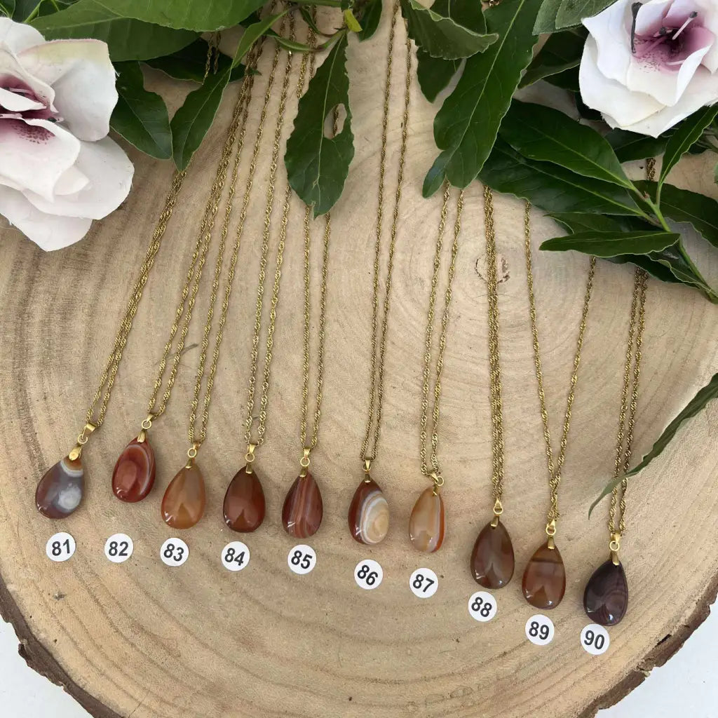 Colliers pendentifs en Cornaline avec chaînes dorées exposés sur une surface en bois naturel