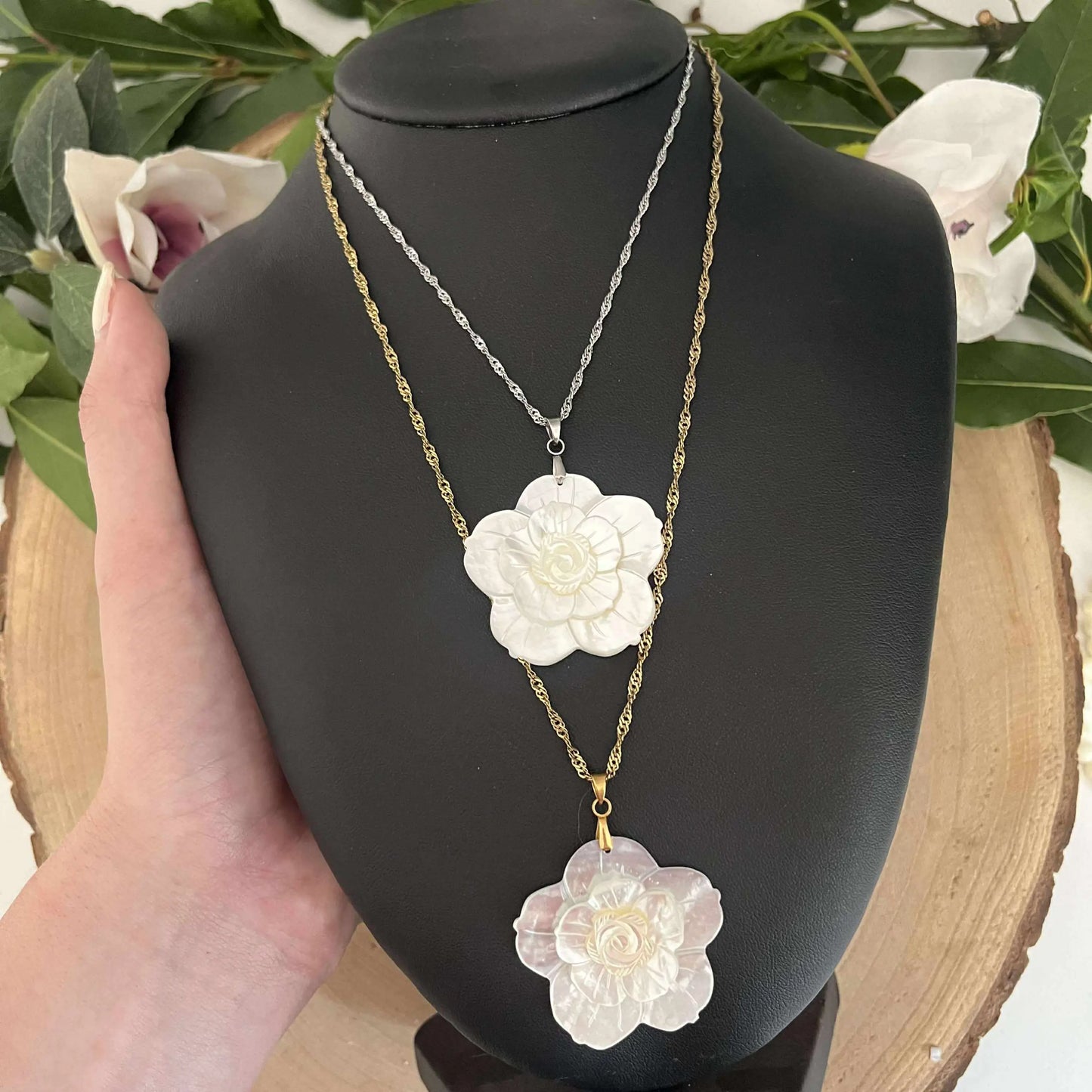 Pendentif Fleur en Nacre Aura de Roche sur chaîne argentée et dorée présenté sur un support noir