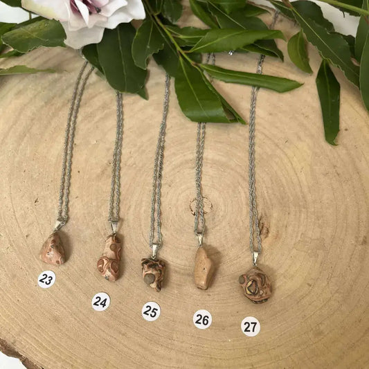 Pendentif Jaspe Léopard en pierre naturelle, élégant et unique, présenté sur un support en bois.