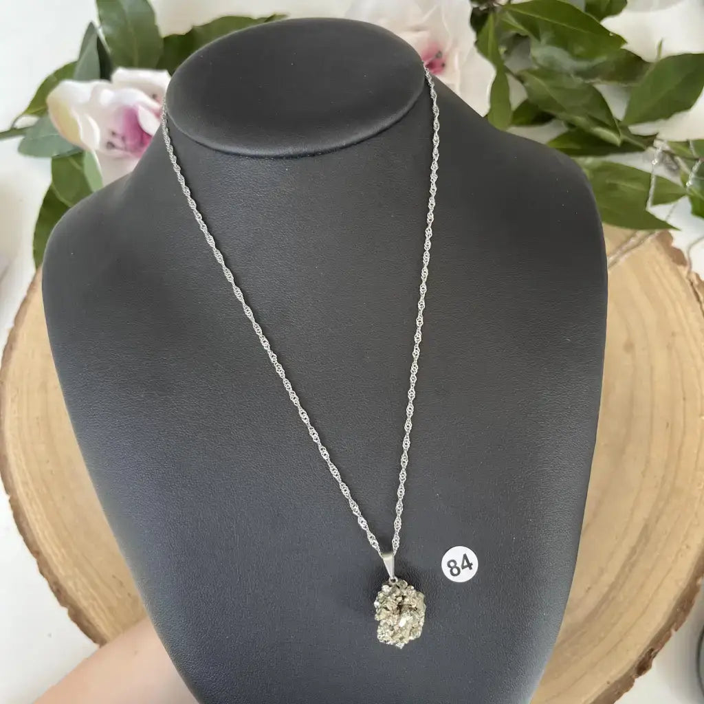 Pendentif Pyrite Brute suspendu sur une chaîne argentée sur un support élégant