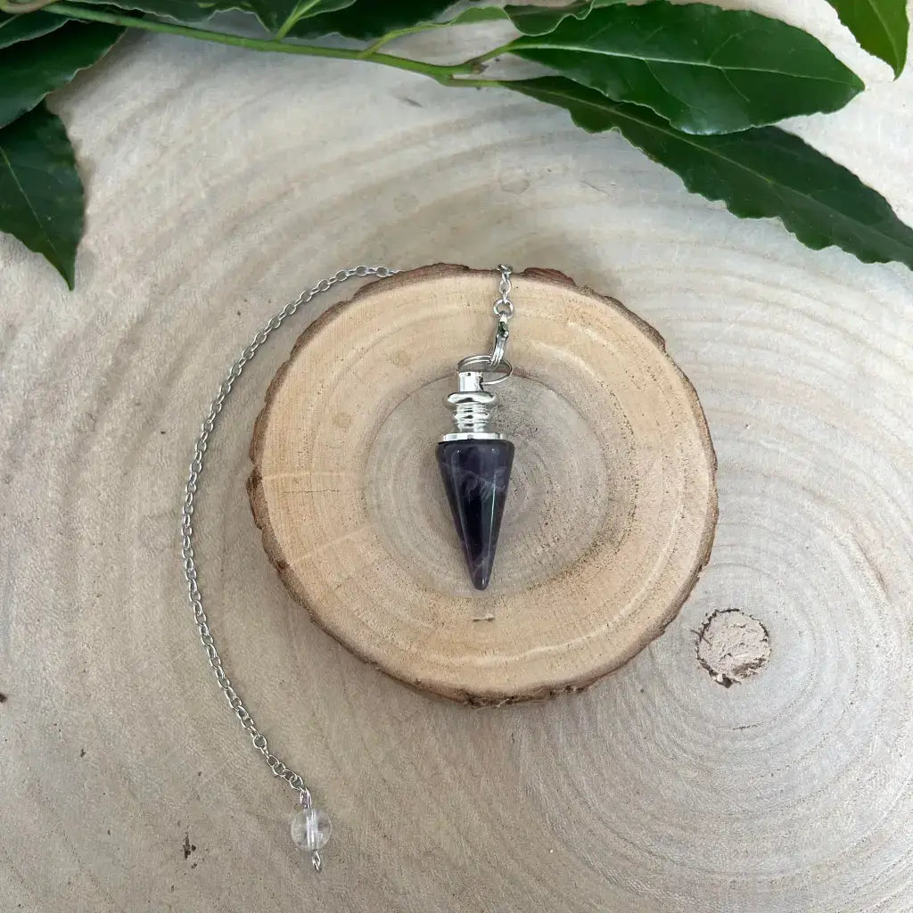 Pendule en Améthyste conique monture argentée avec chaînette et perle transparente sur tranche de bois